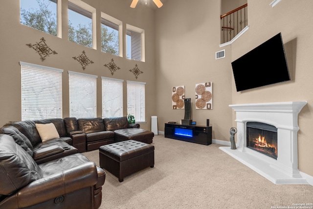 living room with ceiling fan, carpet, and a towering ceiling