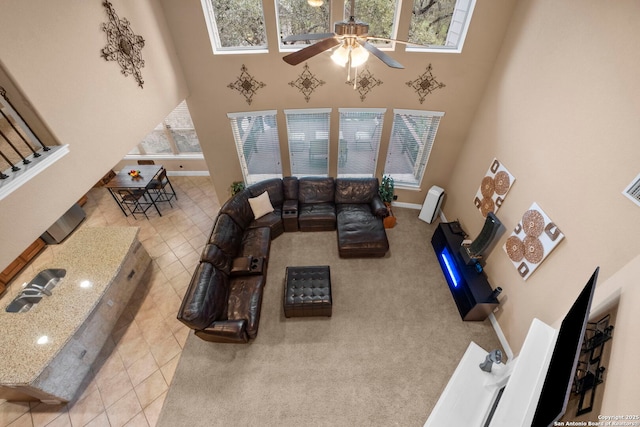 living room featuring light colored carpet, a high ceiling, and ceiling fan