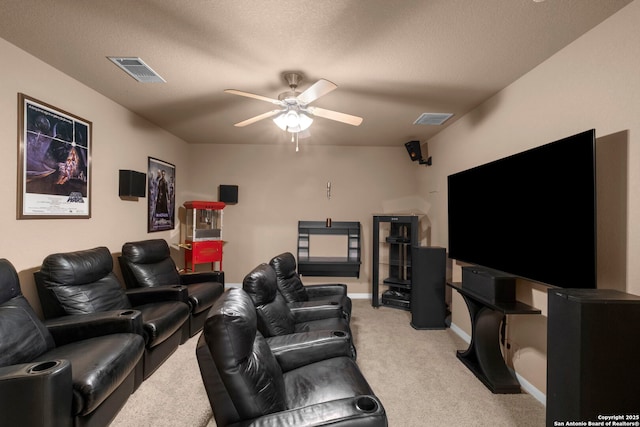 home theater with a textured ceiling, light colored carpet, and ceiling fan