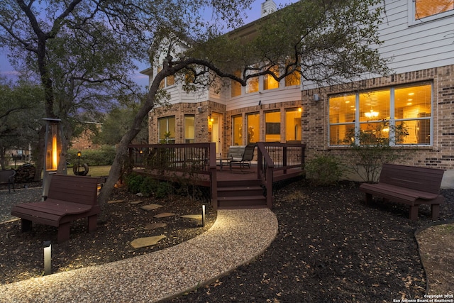 back house at dusk featuring a deck