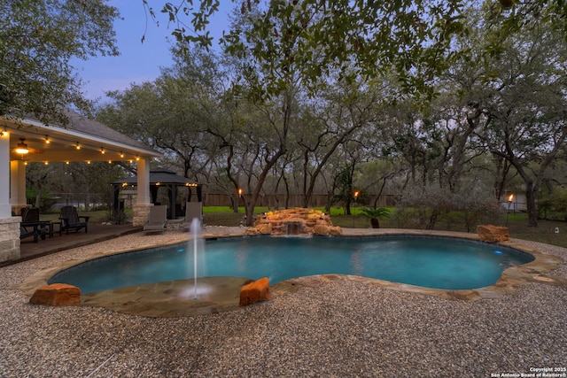 pool at dusk with a gazebo and pool water feature