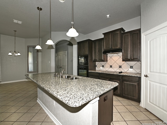 kitchen with dark brown cabinets, an island with sink, black appliances, and sink