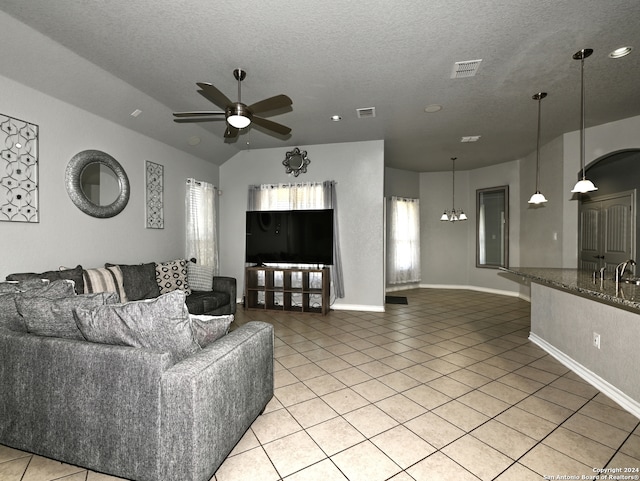 tiled living room featuring ceiling fan with notable chandelier, a textured ceiling, and a wealth of natural light