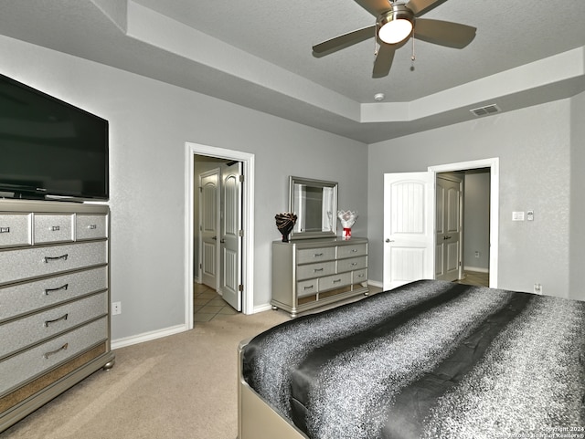 carpeted bedroom with a tray ceiling, ceiling fan, and a textured ceiling