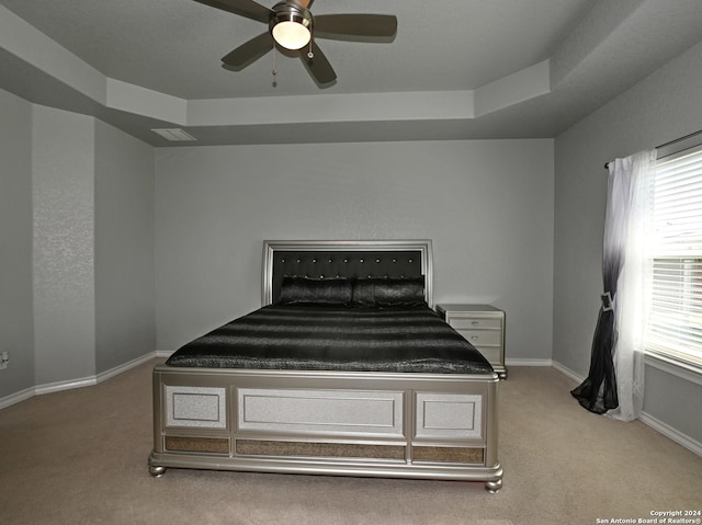 unfurnished bedroom featuring light carpet, a tray ceiling, and ceiling fan