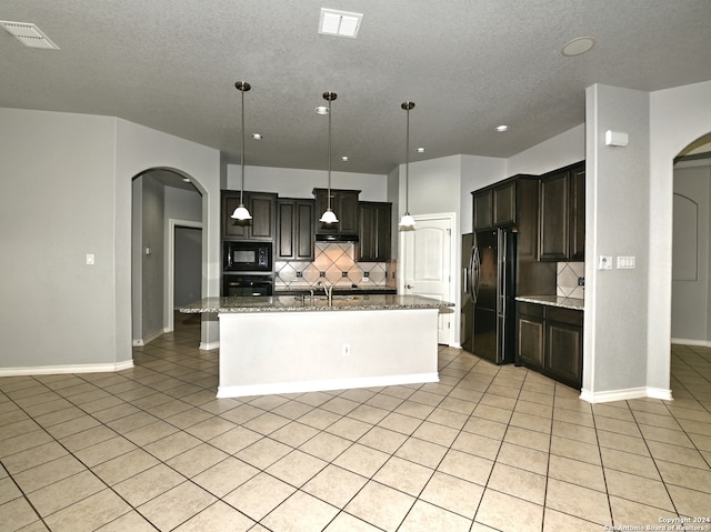 kitchen with backsplash, a kitchen island with sink, pendant lighting, and black appliances