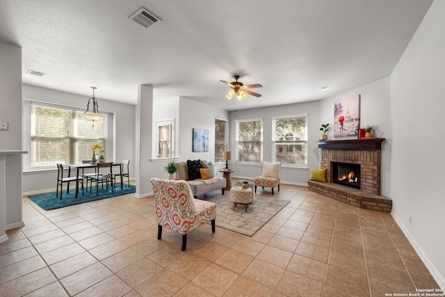 tiled living room featuring a fireplace, a textured ceiling, plenty of natural light, and ceiling fan