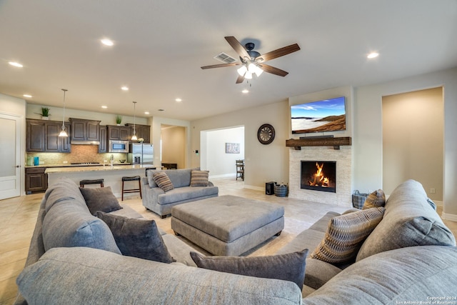 tiled living room with ceiling fan and a fireplace