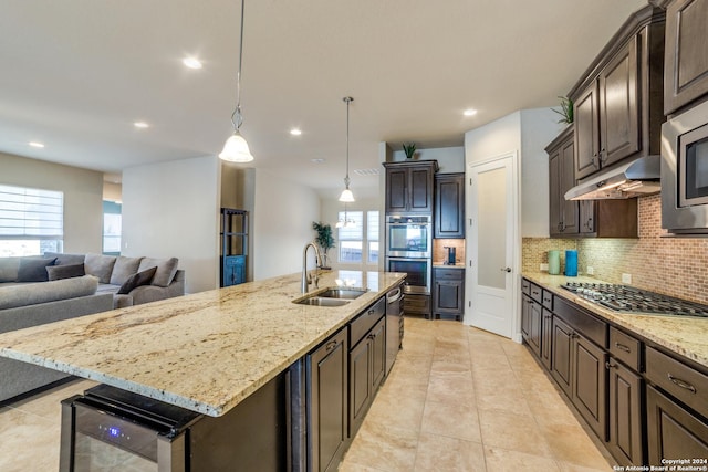 kitchen with sink, wine cooler, decorative light fixtures, a kitchen island with sink, and dark brown cabinets