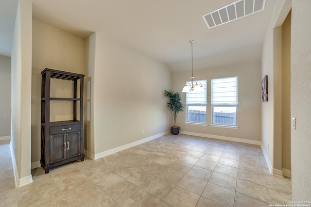 tiled empty room with a chandelier