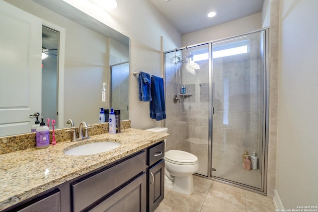 bathroom featuring ceiling fan, tile patterned flooring, toilet, vanity, and a shower with shower door