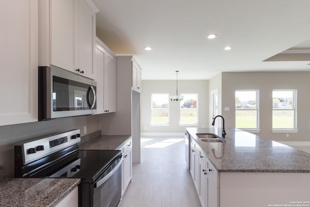 kitchen with sink, white cabinets, decorative light fixtures, and appliances with stainless steel finishes