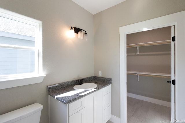 bathroom featuring a wealth of natural light, vanity, wood-type flooring, and toilet