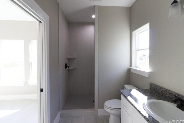 bathroom with a tile shower, vanity, and toilet