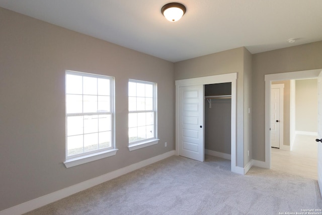 unfurnished bedroom with light colored carpet and a closet