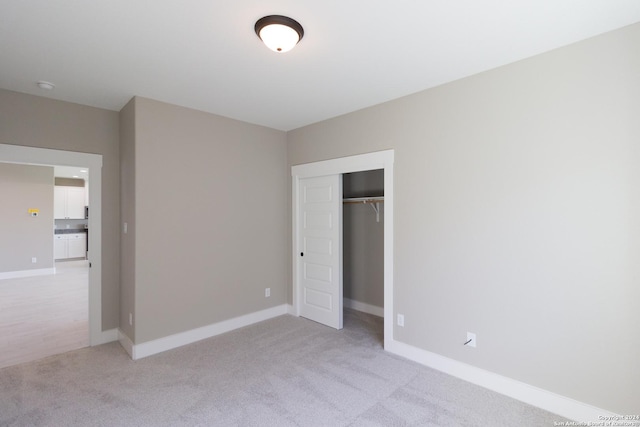 unfurnished bedroom featuring light carpet and a closet