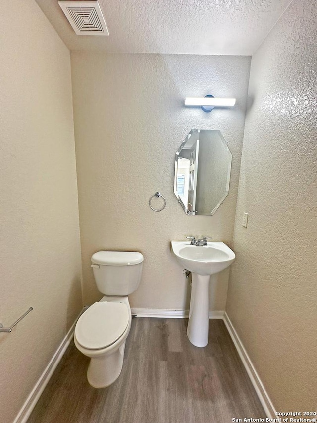 bathroom featuring toilet, wood-type flooring, and a textured ceiling