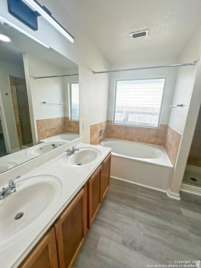 bathroom with vanity, wood-type flooring, a textured ceiling, and independent shower and bath