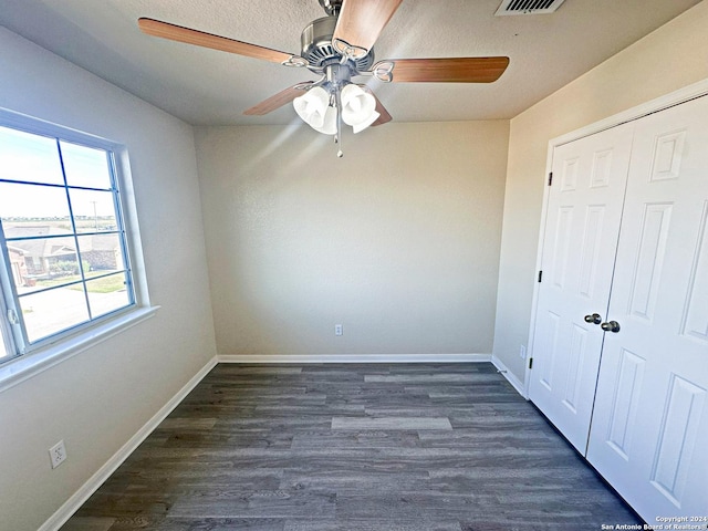 unfurnished bedroom with ceiling fan, dark hardwood / wood-style flooring, and a closet