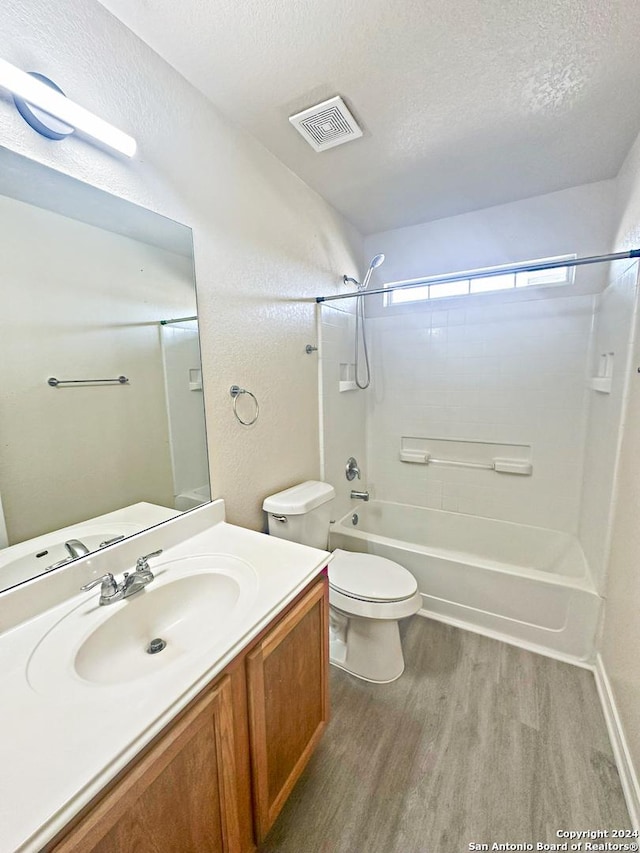 full bathroom with washtub / shower combination, a textured ceiling, toilet, vanity, and hardwood / wood-style flooring