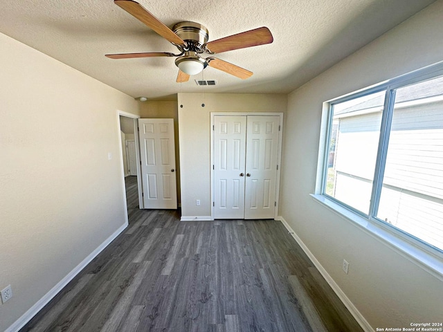 unfurnished bedroom with a textured ceiling, a closet, ceiling fan, and dark wood-type flooring