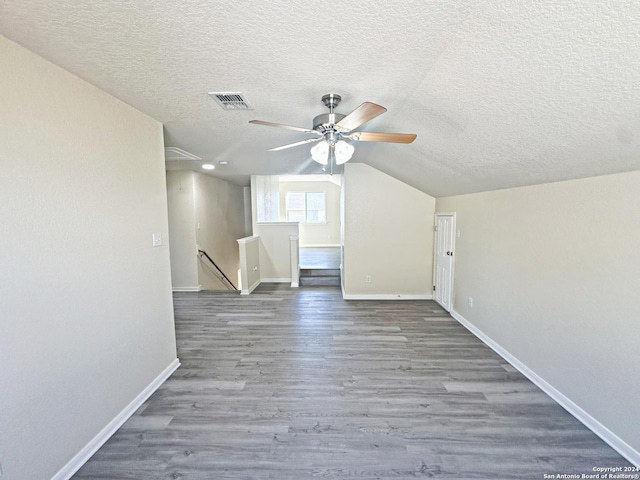 additional living space with hardwood / wood-style floors, ceiling fan, a textured ceiling, and vaulted ceiling