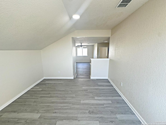 bonus room featuring a textured ceiling, hardwood / wood-style flooring, and lofted ceiling