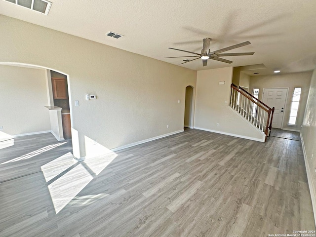 unfurnished living room with ceiling fan, a textured ceiling, and hardwood / wood-style flooring