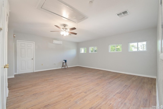 unfurnished room featuring a wall mounted AC, a wealth of natural light, light hardwood / wood-style flooring, and ceiling fan