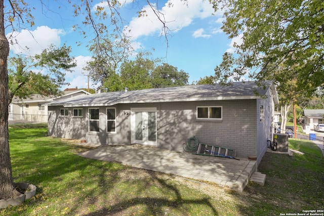 back of property with a lawn, central AC unit, and a patio area