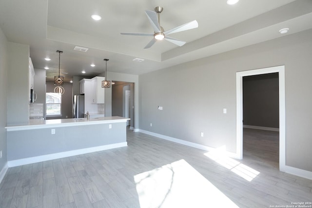 kitchen with white cabinetry, pendant lighting, stainless steel appliances, and light hardwood / wood-style floors