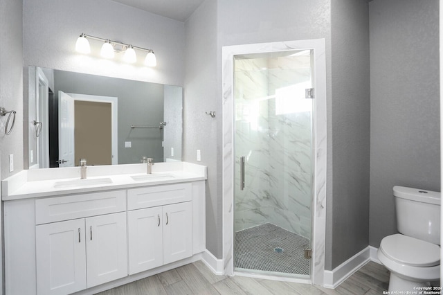 bathroom with wood-type flooring, vanity, toilet, and a shower with shower door