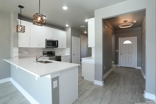 kitchen with white cabinets, sink, decorative light fixtures, kitchen peninsula, and stainless steel appliances