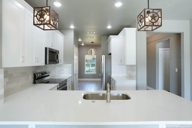 kitchen featuring decorative light fixtures, sink, kitchen peninsula, and stainless steel appliances