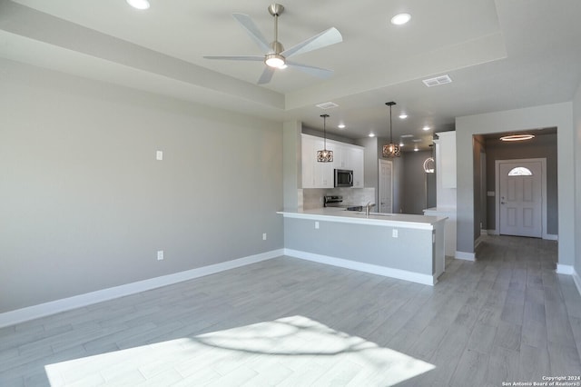 kitchen featuring hanging light fixtures, light hardwood / wood-style flooring, appliances with stainless steel finishes, white cabinetry, and kitchen peninsula