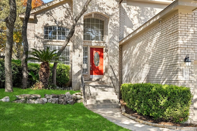 view of exterior entry featuring a lawn