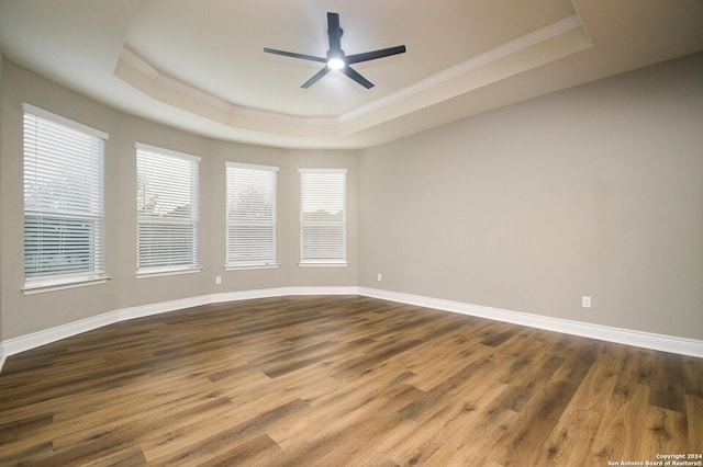 spare room with a tray ceiling, ceiling fan, hardwood / wood-style floors, and ornamental molding