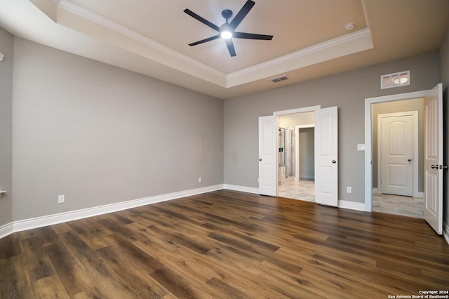 unfurnished bedroom featuring a tray ceiling, ceiling fan, dark hardwood / wood-style floors, and ornamental molding