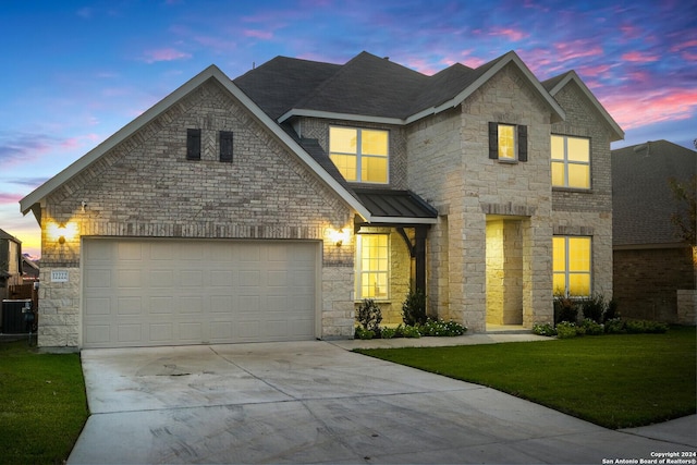 view of front of home with central AC, a garage, and a lawn