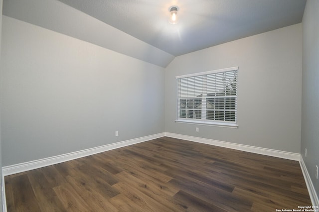 spare room with dark hardwood / wood-style flooring and vaulted ceiling