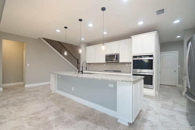 kitchen featuring white cabinets, pendant lighting, a kitchen island with sink, and appliances with stainless steel finishes