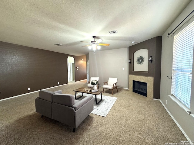 living room featuring carpet flooring, a tile fireplace, a wealth of natural light, and a textured ceiling