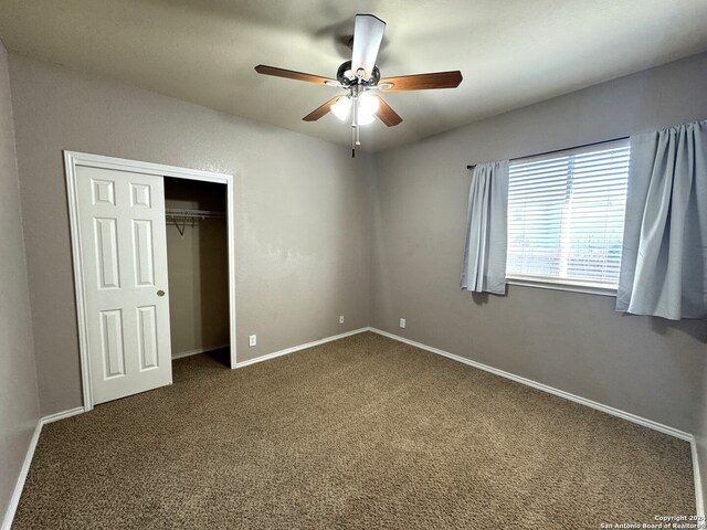 unfurnished bedroom featuring ceiling fan, a closet, and dark carpet