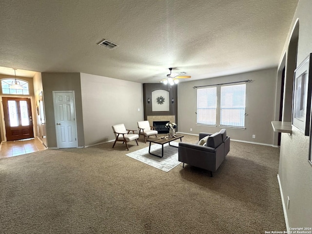 carpeted living room with a textured ceiling, ceiling fan, and a healthy amount of sunlight