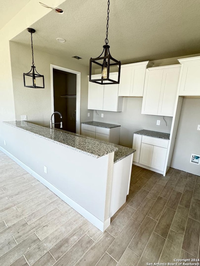 kitchen with a notable chandelier, white cabinets, decorative light fixtures, and light wood-type flooring