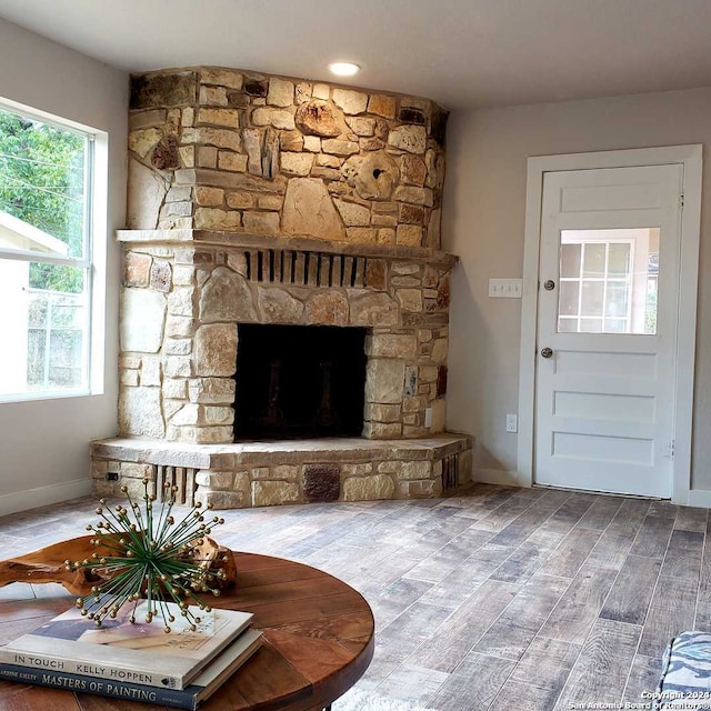 living room with a stone fireplace and hardwood / wood-style floors