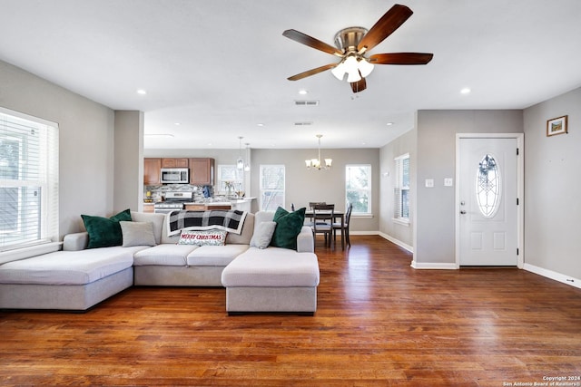 living room featuring ceiling fan with notable chandelier and dark hardwood / wood-style floors