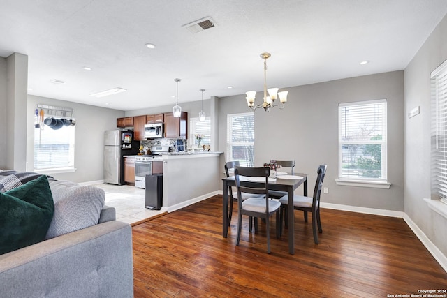 dining space featuring plenty of natural light, dark hardwood / wood-style floors, and an inviting chandelier