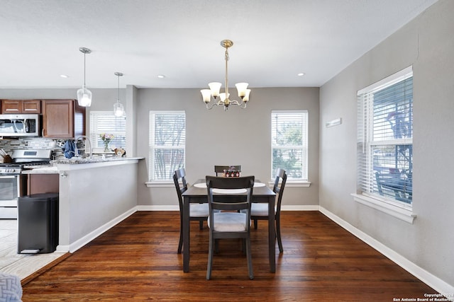 dining room featuring a wealth of natural light, dark wood-type flooring, and an inviting chandelier