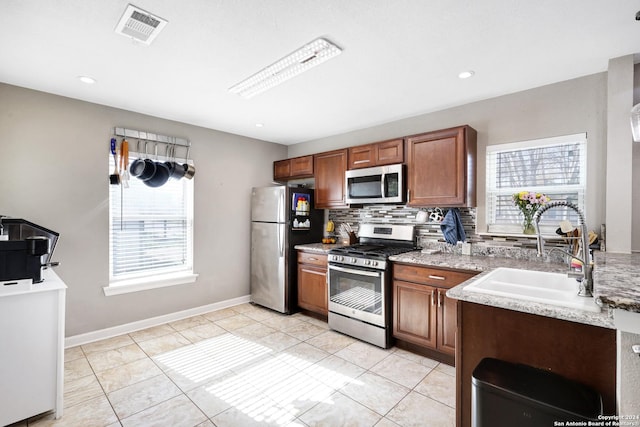 kitchen featuring decorative backsplash, a wealth of natural light, sink, and stainless steel appliances